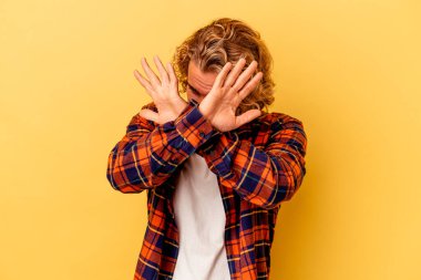 Sarı arka planda izole genç beyaz adam iki kolu çapraz tutuyor, inkar kavramı.