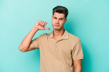 Mavi arka planda izole edilmiş genç beyaz bir adam hoşlanmadığı bir jest yapıyor. Anlaşmazlık konsepti.