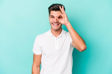 Kafkasyalı genç adam mavi arka planda izole edildi. Heyecanlı görünüyor..