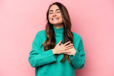 Pembe arka planda soyutlanmış beyaz bir kadın gülüyor, elini yüreğine koyuyor, mutluluk kavramını koruyor..