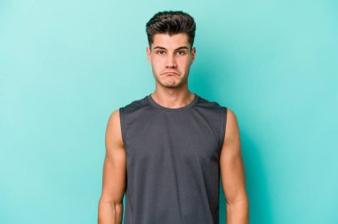 Kafkasyalı genç adam mavi arka planda izole edilmiş üzgün, ciddi yüzlü, mutsuz ve hoşnutsuz..