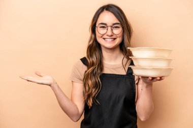 Beyaz tenli genç bir kadın bej arka planda saklanmış tupperware taşıyor. Bir avuç içinde fotokopi alanı ve belinde başka bir el tutuyor..