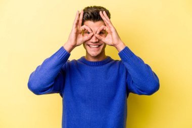 Sarı arka planda izole edilmiş genç beyaz adam gözlerinde sorun olmadığını gösteriyor.