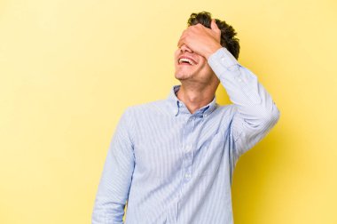 Sarı arka planda izole edilmiş genç beyaz adam ellerini başının üstünde tutarak neşe içinde gülüyor. Mutluluk kavramı.