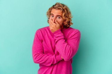 Kafkasyalı genç adam mavi arka planda izole edilmiş korkmuş ve korkmuş..