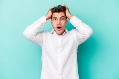 Kafkasyalı genç adam mavi arka planda izole edildi. Şaşırdı ve şok oldu..