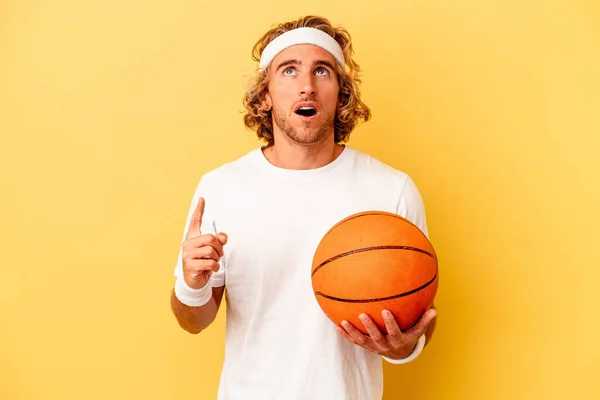 Молодой Баскетболист Белый Мужчина Выделенный Желтом Фоне Указывая Вверх Ногами — стоковое фото