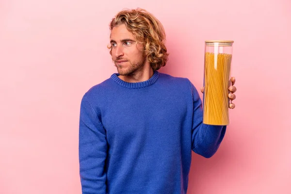 Young Caucasian Man Holding Spaghettis Jar Isolated Pink Background Looks — Zdjęcie stockowe