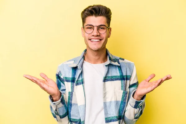 Jovem Caucasiano Isolado Fundo Amarelo Faz Escala Com Braços Sente — Fotografia de Stock