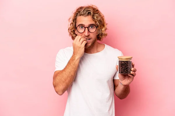 Young Caucasian Man Holding Coffee Jar Isolated Pink Background Biting — Zdjęcie stockowe