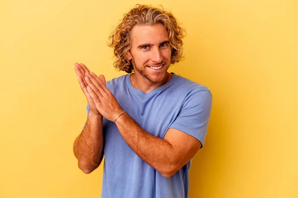 Young caucasian man isolated on yellow background feeling energetic and comfortable, rubbing hands confident.