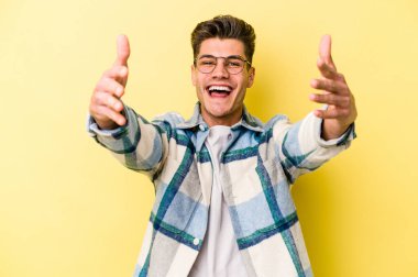 Sarı arka planda izole edilmiş genç beyaz bir adam zaferi ya da başarıyı kutluyor, şaşırıyor ve şok oluyor..