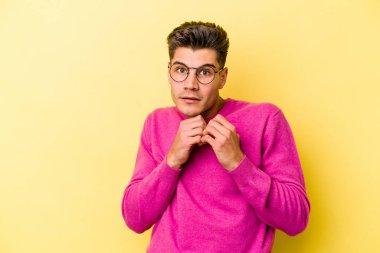 Sarı arka planda izole edilmiş genç beyaz adam korkmuş ve korkmuş..