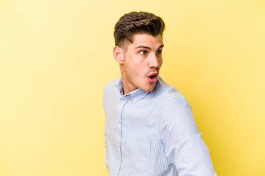 Sarı arka planda izole edilmiş genç beyaz adam gülümseyen, neşeli ve keyifli görünüyor..