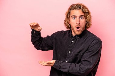 Pembe arka planda izole edilmiş genç beyaz adam elleri arasında bir fotokopi alanı tutuyor..