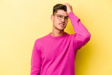 Sarı arka planda izole edilmiş genç beyaz bir adam bir şeyi unutuyor. Alnına avuç içi ve gözlerini kapayarak vuruyor..