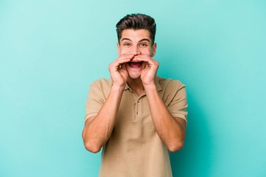 Kafkasyalı genç adam mavi arka planda izole edilmiş. Dedikodu yapıyor, bir şeyleri bildiriyor..