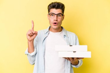 Sarı arka planda pizza tutan beyaz bir adam harika bir fikre, yaratıcılık kavramına sahip..