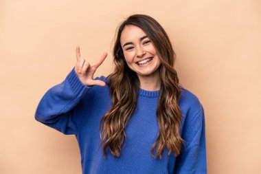 Beyaz tenli genç bir kadın bej arka planda izole edilmiş boynuzlarını devrim konsepti olarak gösteriyor..