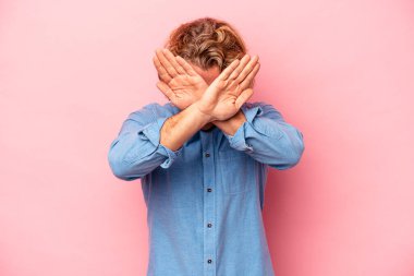 Pembe arka planda izole genç beyaz adam iki kolu çapraz tutuyor, inkar kavramı.