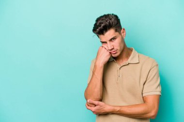 Mavi arka planda izole edilmiş, üzgün ve dalgın hisseden, kopyalama alanına bakan genç beyaz bir adam..