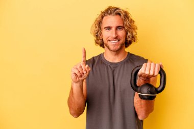 young sport man making weightlifting isolated on yellow background showing number one with finger.