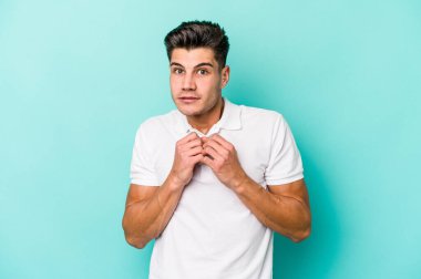 Kafkasyalı genç adam mavi arka planda izole edilmiş korkmuş ve korkmuş..