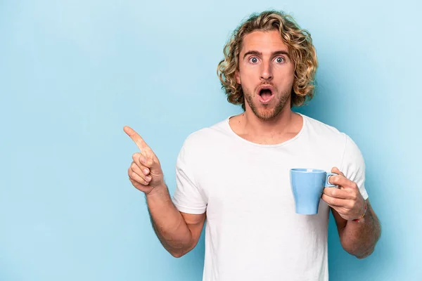 Young Man Holding Mug Isolated Blue Background Pointing Side — Foto de Stock