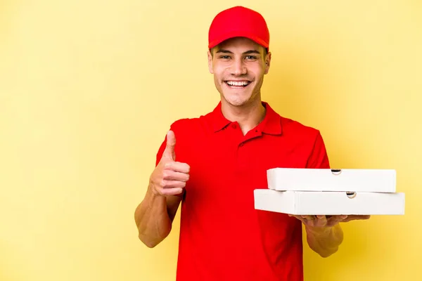 Young Delivery Caucasian Man Holding Pizzas Isolated Yellow Background Smiling — ストック写真