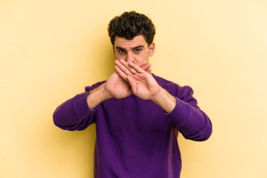 Sarı arka planda izole edilmiş genç beyaz adam inkar jesti yapıyor.