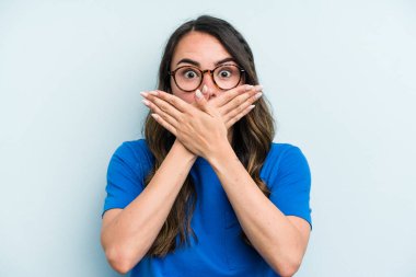 Mavi arka planda izole edilmiş beyaz bir kadın elleriyle ağzını kapatırken şok oldu..