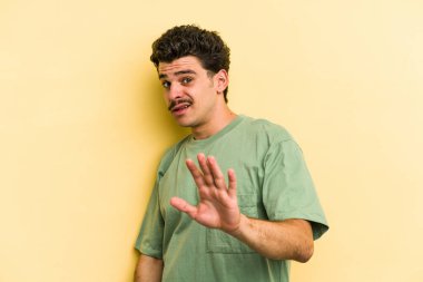 Sarı arka planda izole genç beyaz adam yakın bir tehlike nedeniyle şoka uğruyor