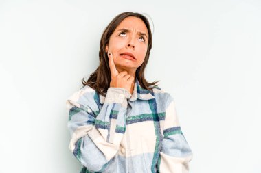 Mavi arka planda izole edilmiş genç İspanyol kadın yorgun ve uykulu ellerini başının üstünde tutuyor..