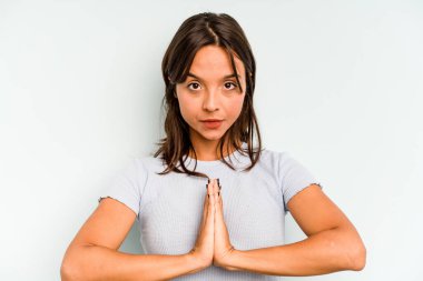 Mavi arka planda izole edilmiş, tırnak yiyen, gergin ve endişeli genç bir kadın..