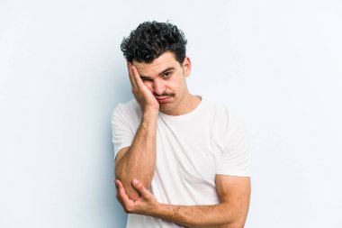 Mavi arka planda izole edilmiş, sıkılmış, yorgun ve dinlenmeye ihtiyacı olan genç beyaz bir adam..
