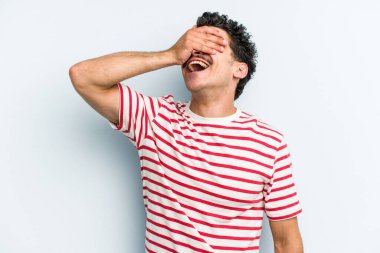 Mavi arka planda izole edilmiş genç beyaz adam ellerini başının üstünde tutarak neşe içinde gülüyor. Mutluluk kavramı.