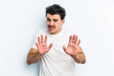 Mavi arka planda izole edilmiş genç beyaz adam tiksinti belirtisi gösteren birini reddediyor..