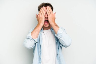 Beyaz arka planda izole edilmiş genç beyaz bir adam yüzünün yarısını palmiye ile örterek eğleniyor..