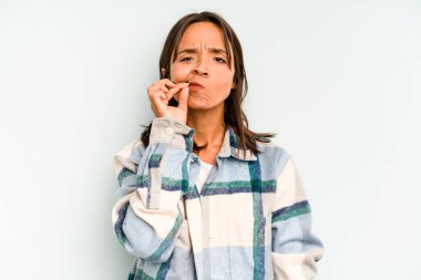 Genç İspanyol kadın, mavi arka planda izole edilmiş. Oturaklı yaşam tarzından dolayı boyun ağrısı çekiyor..