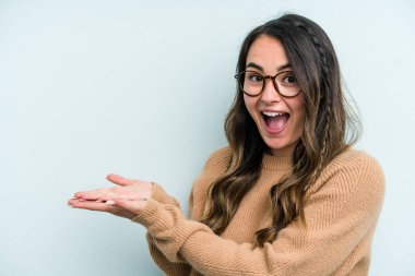 Mavi arka planda izole edilmiş beyaz bir kadın. Elinde palmiye ağacında bir kopya alanı var..