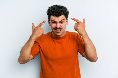 Mavi arka planda izole edilmiş genç beyaz adam işaret parmağıyla bir hayal kırıklığı jesti gösteriyor..