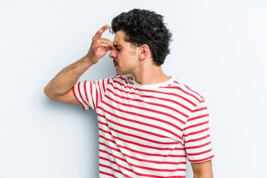 Kafkasyalı genç bir adam mavi arka planda izole edilmiş, başı ağrıyor, yüzüne dokunuyor..