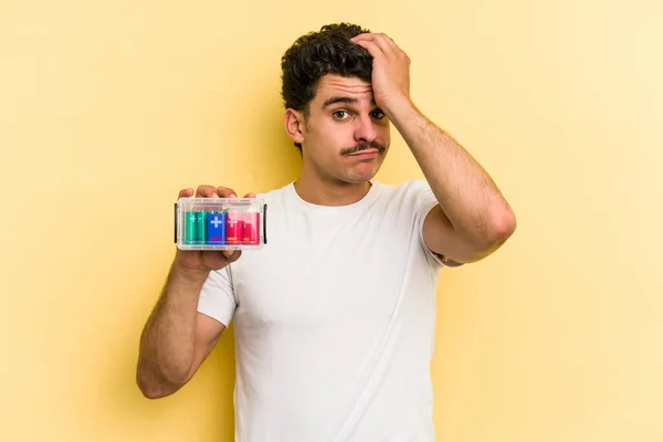 Young Caucasian Man Holding Batteries Isolated Yellow Background Being Shocked — 图库照片