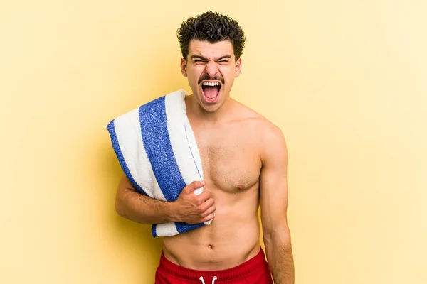 Young Caucasian Man Holding Beach Towel Isolated Yellow Background Screaming — Photo