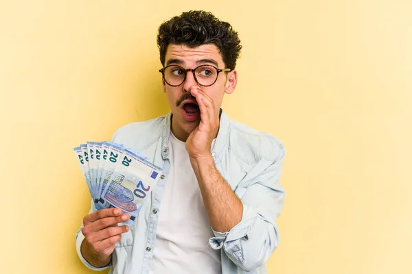 Young Caucasian Man Holding Banknotes Isolated Yellow Background Saying Secret — Foto de Stock