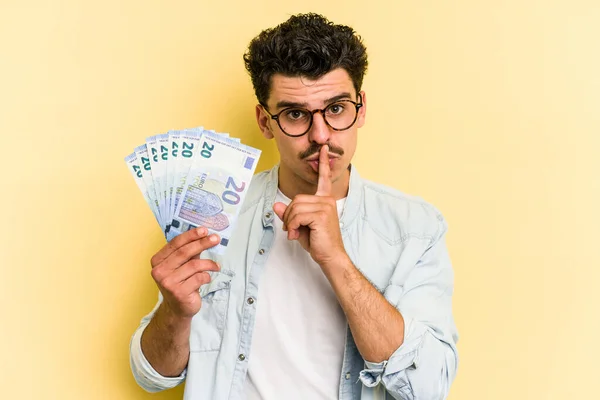 Young Caucasian Man Holding Banknotes Isolated Yellow Background Keeping Secret — Foto de Stock