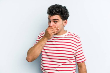 Kafkasyalı genç adam mavi arka planda izole edilmiş ağzı kapalı ve elleri endişeli görünüyor..