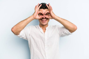 Kafkasyalı genç adam mavi arka planda izole edildi. Heyecanlı görünüyor..