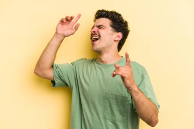 Genç beyaz adam sarı arka planda izole edilmiş dans ediyor ve eğleniyor..