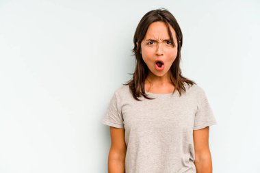 Mavi arka planda izole edilmiş genç İspanyol kadın pençelerini bir kediyi taklit ederken gösteriyor, agresif bir hareket..